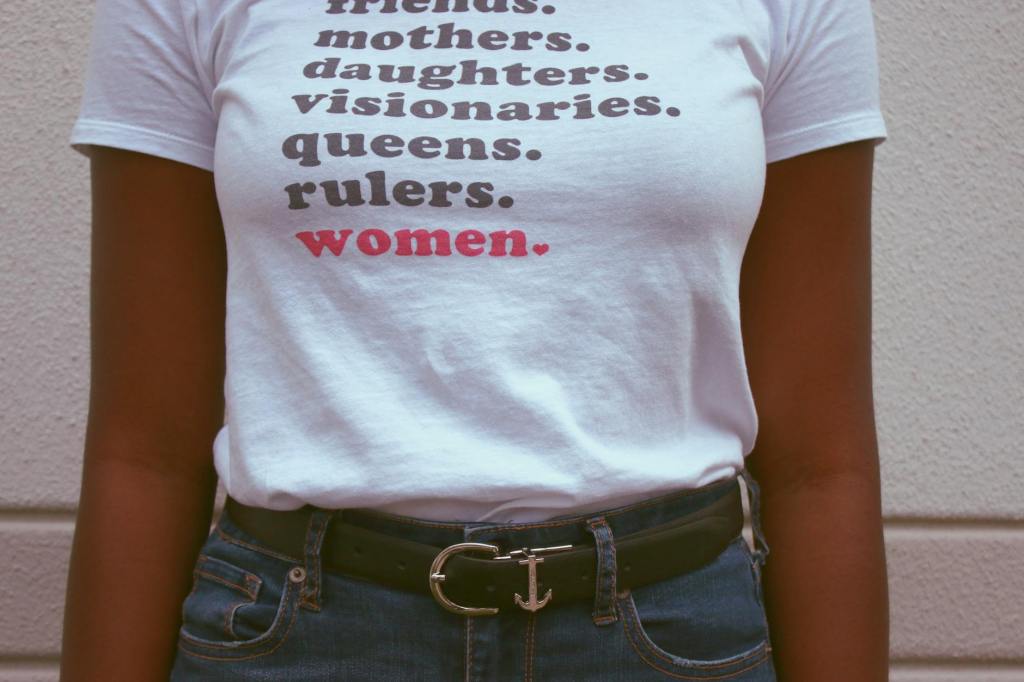 Mulher com t-shirt onde se lê "mothers. daughters. visionaries. queens. rulers. women."